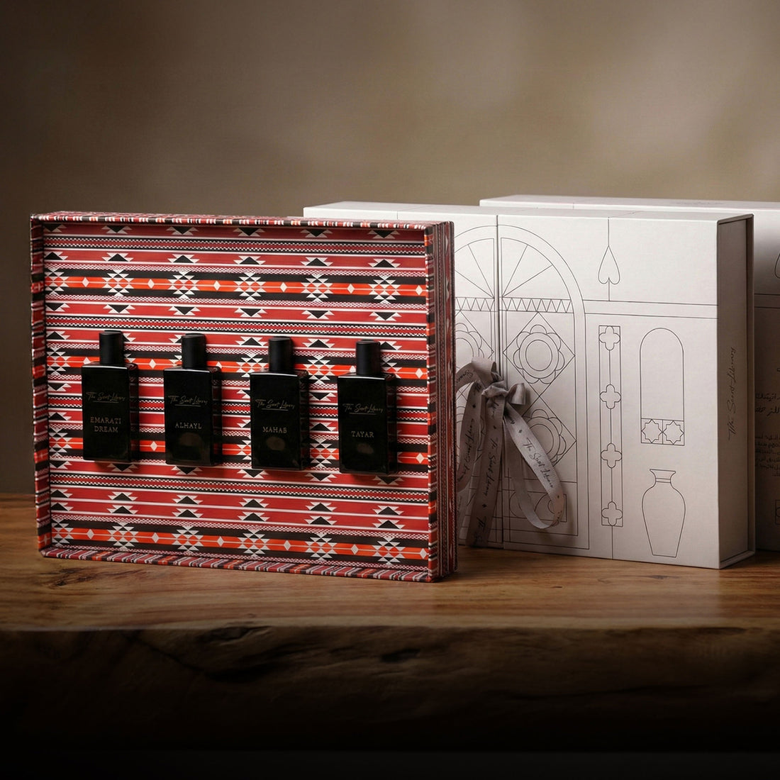 The Private Collection by Baytak, four black perfume bottles in a red Sadu-patterned gift box beside a white presentation box, by The Scent Library